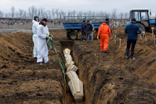Ukladanie rakiev do spoločného hrobu pri Ruskom okupovanom Mariupole. FOTO: Reuters