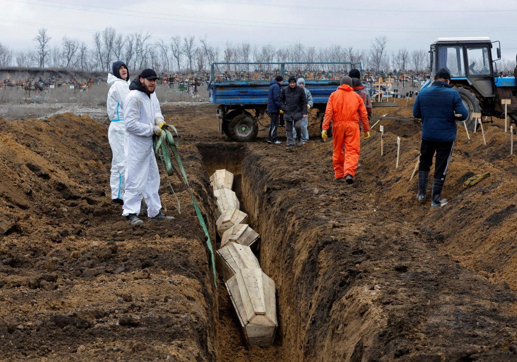 Ukladanie rakiev do spoločného hrobu pri Ruskom okupovanom Mariupole. FOTO: Reuters