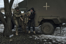 Ukrajinskí vojaci pomáhajú poranenému spolubojovníkovi dostať sa do evakuačného vozidla na frontovej línii v meste Bachmut v Doneckej oblasti na východe Ukrajiny. FOTO: TASR/AP