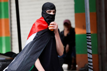 Muž v maske s palestínskou vlajkou. FOTO: Reuters
