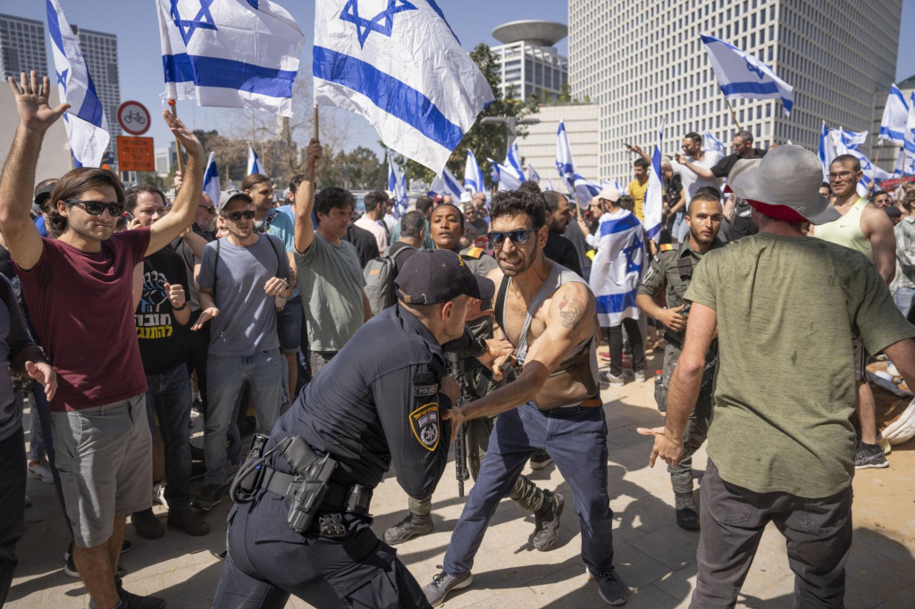 Izraelský policajt sa bije s demonštrantmi, ktorí sa pokúšajú blokovať hlavnú cestu počas protestu proti vládnemu návrhu súdnej reformy nového premiéra Benjamina Netanjahua v Tel Avive. FOTO: TASR/AP