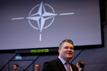 Fínsky minister obrany Mikko Savola a symbol NATO. FOTO: Reuters