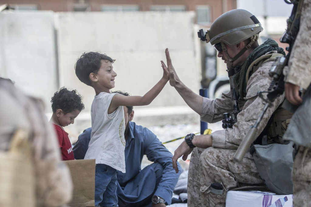 Nie každý americký vojak je ako filmový Rambo. Tento vojak si dáva high five s afganským chlapcom počas evakuácie na medzinárodnom letisku Hamída Karzaja v Kábule. FOTO: TASR/AP