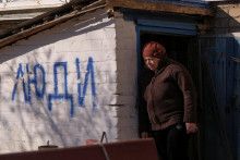 Obyvateľka ukrajinského mesta Siversk stojí vedľa nápisu v znení ”ľudia”. FOTO: Reuters
