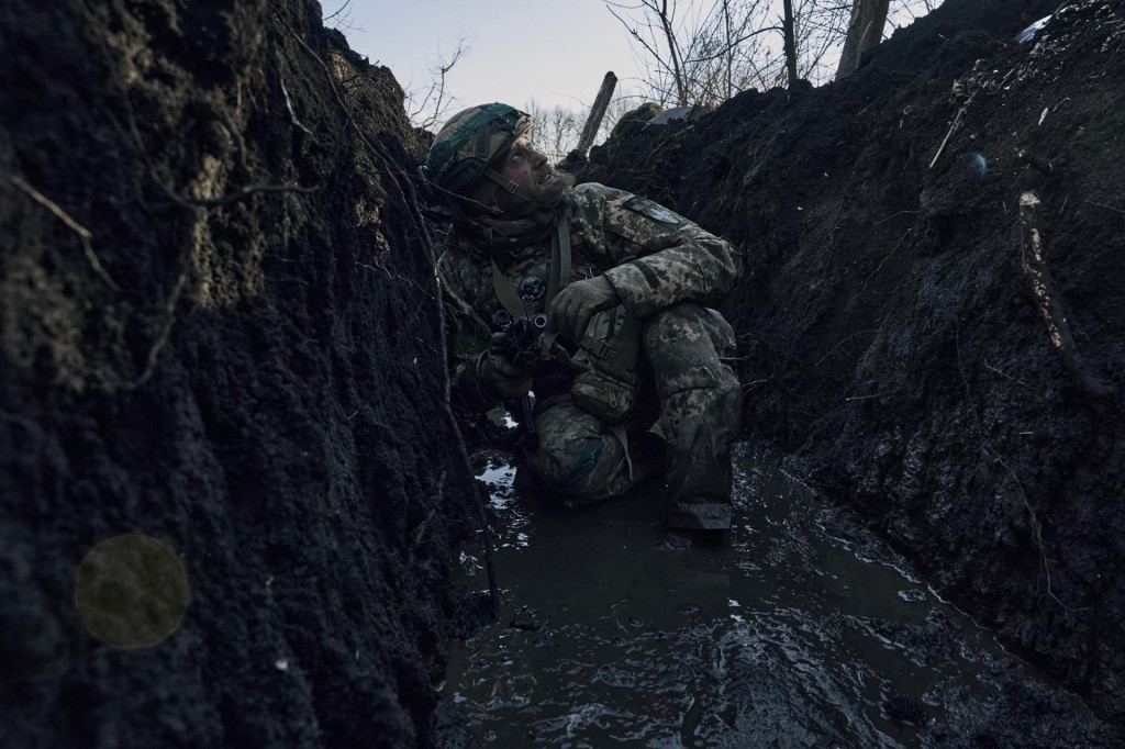 Ukrajinský vojak sa ukrýva v zákope pred ruskou paľbou na frontovej línii neďaleko mesta Bachmut v Doneckej oblasti na východe Ukrajiny. FOTO: TASR/AP