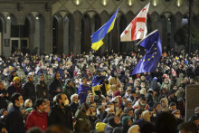 Demonštranti mávajú vlajkami zľava Ukrajiny, Gruzínska a Európskej únie počas protestu pred budovou parlamentu v Tbilisi. Protestom vyjadrili nesúhlas s prerokúvaným zákonom o agentoch zahraničného vplyvu.  FOTO: TASR/AP