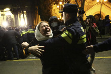Policajt zatýka demonštrantku počas protestu pred budovou parlamentu v Tbilisi. FOTO: TASR/AP