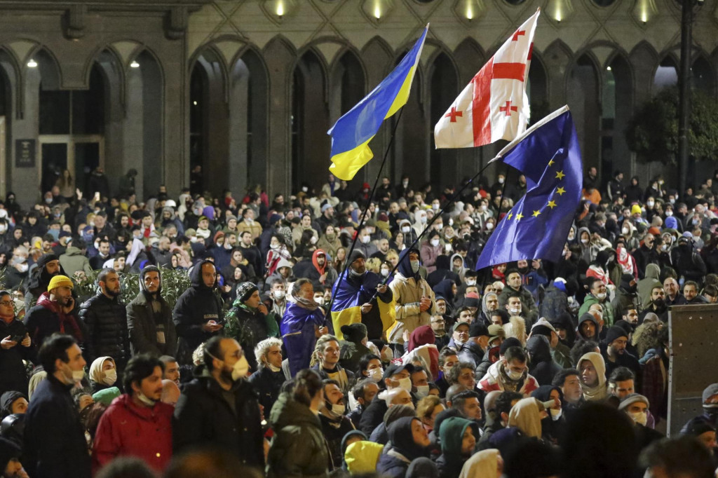 Demonštranti mávajú vlajkami zľava Ukrajiny, Gruzínska a Európskej únie počas protestu pred budovou parlamentu v Tbilisi. Protestom vyjadrili nesúhlas s prerokúvaným zákonom o agentoch zahraničného vplyvu.  FOTO: TASR/AP