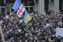 Protestujúci sa zhromažďujú s americkými, gruzínskymi, ukrajinskými vlajkami a vlajkami Európskej únie pred budovou gruzínskeho parlamentu v Tbilisi. FOTO: TASR/AP