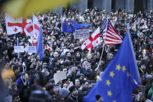 Protestujúci sa zhromažďujú s americkými, gruzínskymi, ukrajinskými vlajkami a vlajkami Únie pred budovou gruzínskeho parlamentu v Tbilisi. FOTO: TASR/AP
