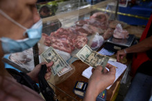 Zákazník platí za svoj nákup v amerických dolároch na otvorenom trhu s ovocím a zeleninou v Caracase vo Venezuele. FOTO: Reuters