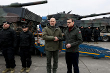 Ukrajinský premiér Denys Šmyhaľ a poľský premiér Mateusz Morawiecki si podávajú ruky vedľa prvých tankov Leopard 2 dodaných z Poľska na Ukrajinu, 24. februára 2023. FOTO: REUTERS