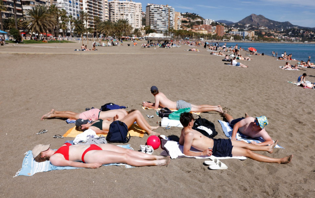 Turisti si užívajú nezvyčajne teplý včerajší večer (11.3.) na pláži v španielskej Malage. FOTO: Reuters