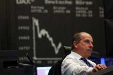Burzový maklér sedí pred grafom indexu cien akcií DAX po tom, ako akcie Credit Suisse dosiahli rekordné minimum. FOTO: Reuters