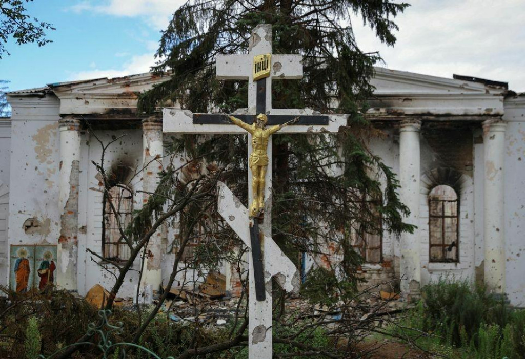 Poškodený pravoslávny kríž pred budovou ostreľovanou počas ruskej invázie v meste Popasna v Luhanskej oblasti na Ukrajine. FOTO: Reuters
