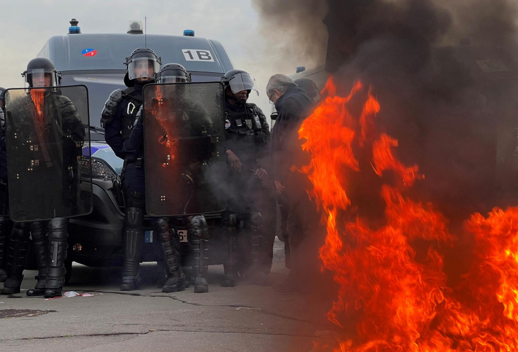 Francúzski policajti a poriadková polícia CRS stoja v blízkosti požiaru, kde sa demonštranti zhromažďujú. FOTO: Reuters