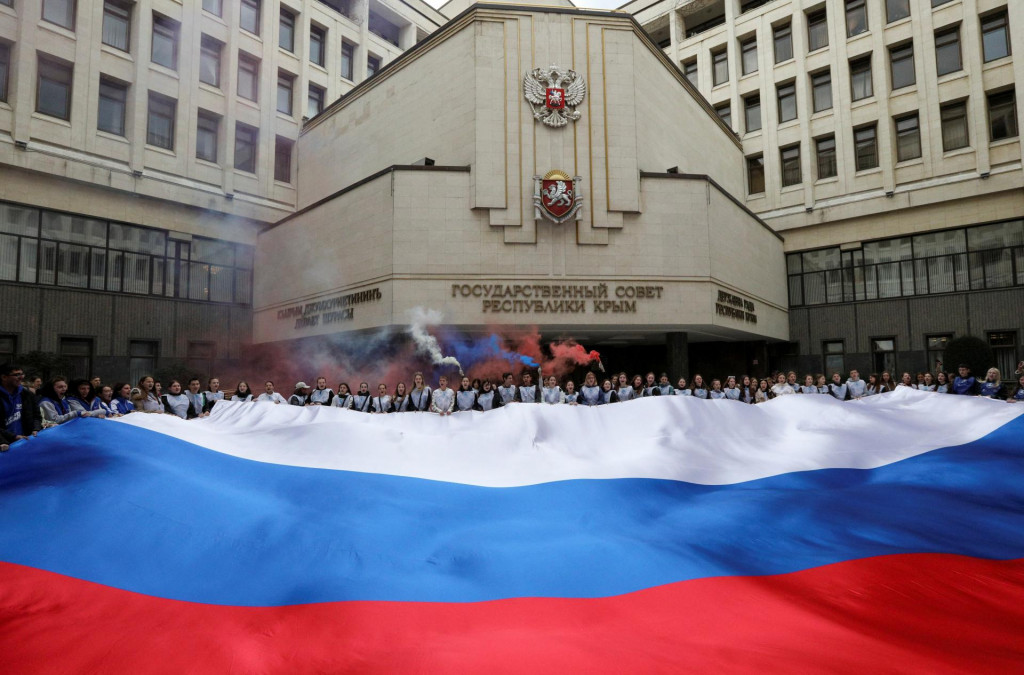 Účastníci sa zhromažďujú okolo obrovskej ruskej štátnej vlajky pred sídlom miestneho parlamentu pri príležitosti deviateho výročia ruskej anexie Krymu v Simferopole na Kryme. FOTO: Reuters