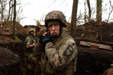 Ukrajinsk&yacute; vojak 1. tankovej brig&aacute;dy si upravuje prilbu v z&aacute;kope počas prich&aacute;dzaj&uacute;ceho delostreleck&eacute;ho ostreľovania na fronte pri ukrajinskom Donecku. FOTO: Reuters