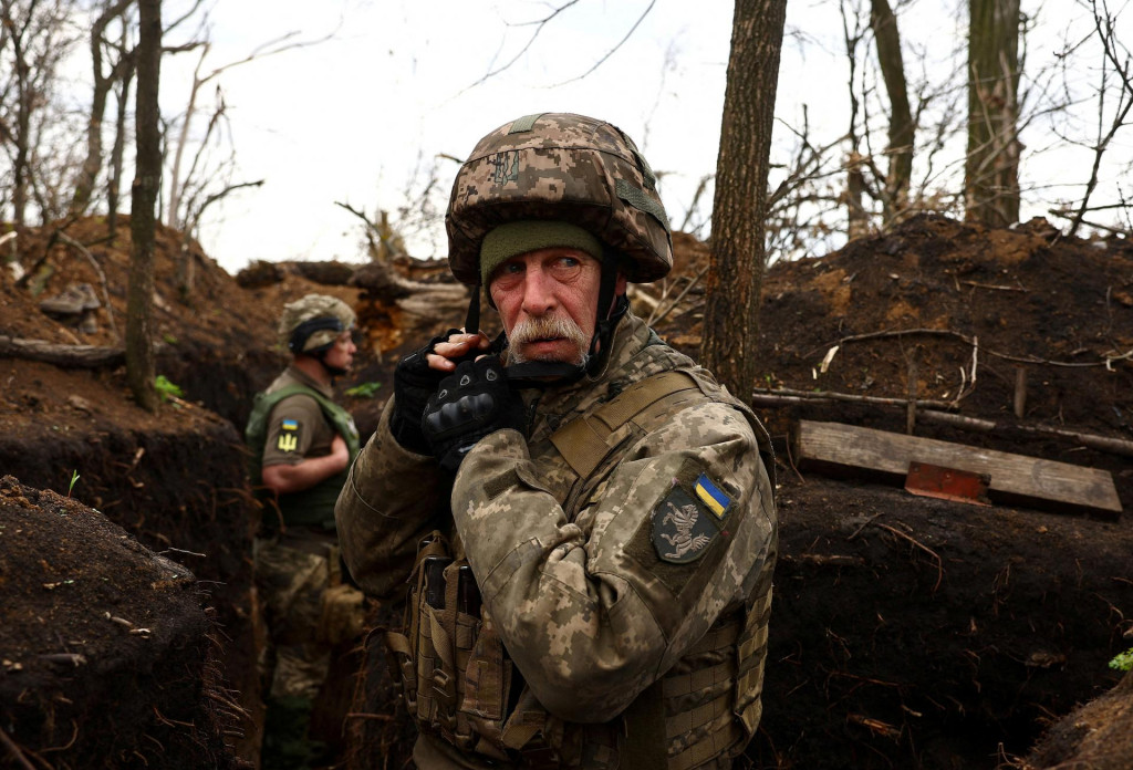 Ukrajinský vojak 1. tankovej brigády si upravuje prilbu v zákope počas prichádzajúceho delostreleckého ostreľovania na fronte pri ukrajinskom Donecku. FOTO: Reuters