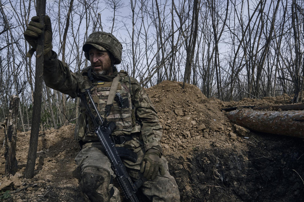 Ukrajinský vojak sa pozerá zo zákopu na frontovej línii v Bachmute. FOTO: TASR/AP