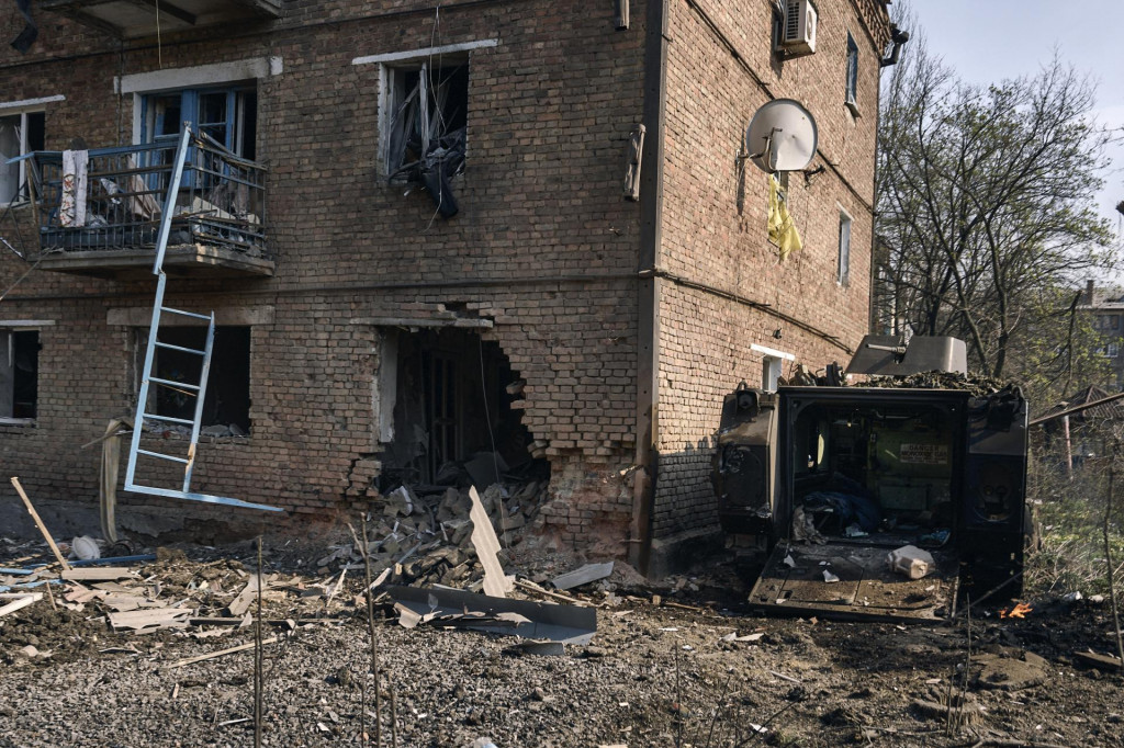 Vrak obrneného vozidla sa nachádza pri zničenom činžiaku v meste Bachmut. FOTO: TASR/AP