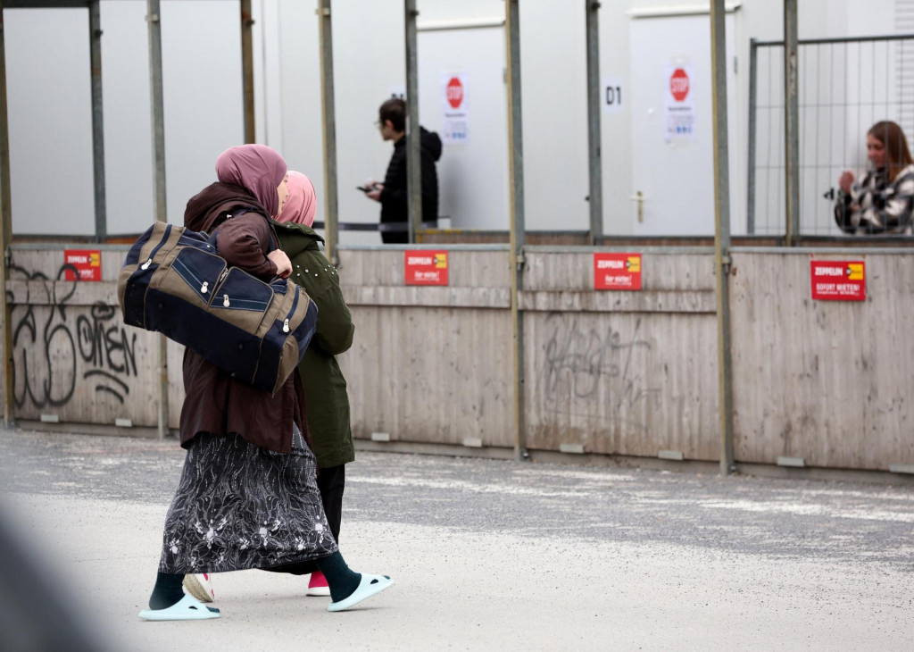 Ľudia kráčajú s taškami v príletovom a dočasnom ubytovacom stredisku pre ukrajinských utečencov na bývalom letisku Tegel v Berlíne. ILUSTRAČNÁ SNÍMKA: Reuters