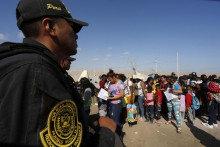 Peruánsky policajt stojí na stráži pri migrantoch bez dokladov, väčšinou z Venezuely, Kolumbie a Haiti, ktorí zostávajú uviaznutí v Čile. FOTO: Reuters