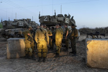 Izraelskí vojaci stoja vedľa tanku neďaleko hranice Izraela s pásmom Gazy. FOTO: TASR/AP