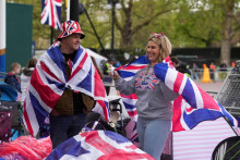 Kráľovskí fanúšikovia nosia vlajky Union Jack pred Buckinghamským palácom pred korunováciou britského kráľa Charlesa a Camilly, kráľovnej manželky, v Londýne. FOTO: Reuters