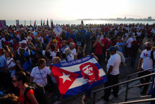 Ľudia nesú kubánsku vlajku s podobizňou neskorého revolučného hrdinu Ernesta „Che“ Guevaru.  FOTO: Reuters