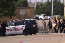 Ľudia držia ruky nad hlavami, keď vychádzajú po streľbe z nákupného centra v meste Allen pri Dallase, v americkom štáte Texas. FOTO: TASR/AP