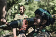 Ukrajinsk&yacute; vojak nesie raketu do raketometu Grad, aby ju vystrelil na rusk&eacute; poz&iacute;cie na fronte pri Bachmute. FOTO: TASR/AP