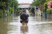 Muž jazdí na bicykli cez záplavy po silných dažďoch, ktoré zasiahli Taliansko. FOTO: Reuters