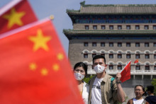 Pár drží čínsku národnú zástavu na Námestí nebeského pokoja (Tchien-an-men) počas májového sviatku práce v Pekingu. FOTO: TASR/AP