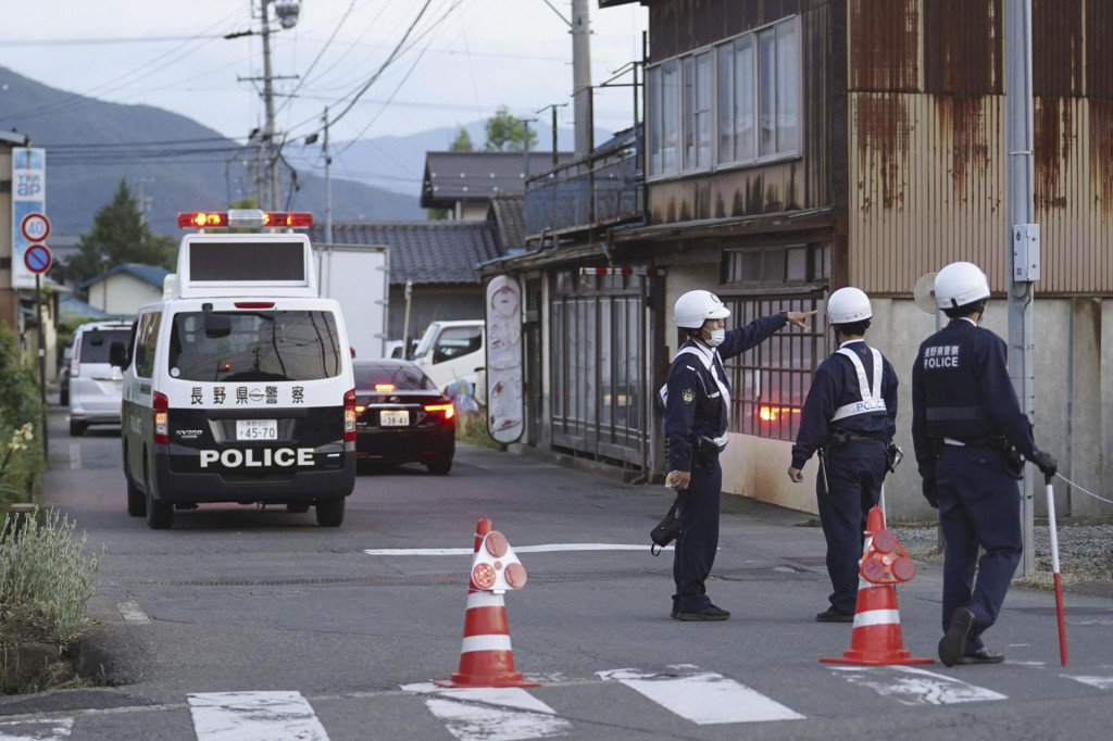 Policajti hliadkujú na ulici vedúcej k budove, kde sa ukrýva muž po streľbe v meste Nakano, v centrálnom Japonsku. FOTO: TASR/AP