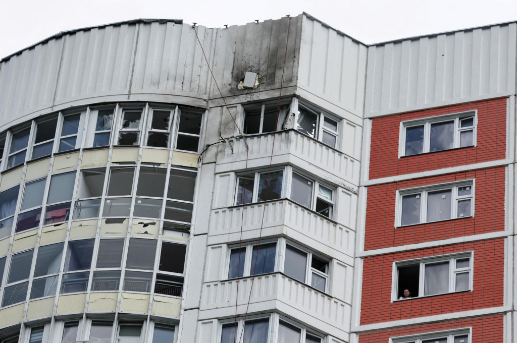 Žena sa pozerá z okna poškodeného viacposchodového bytového domu po ohlásenom útoku dronu v Moskve. FOTO: Reuters