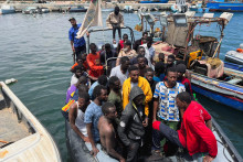 Migranti, ktorých člny sa potopili v mori a ktorých zachránila líbyjská pobrežná stráž v Stredozemnom mori, prichádzajú na člne do prístavu v Garaboli v Líbyi. FOTO: Reuters