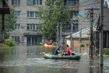 Miestni obyvatelia sa plavia na člnoch na zaplavenej ulici počas evakuácie po pretrhnutí priehrady Nová Kachovka. FOTO: Reuters