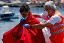 Člen Červeného kríža pomáha migrantovi po vylodení z plavidla španielskej pobrežnej stráže v prístave Arguineguin na ostrove Gran Canaria. FOTO: Reuters