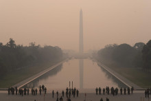 Ľudia stoja pred zadymeným Washingtonským pamätníkom vo Washingtone. FOTO TASR/AP
