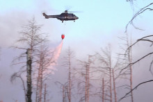 Vrtuľník vylieva vodu z vaku počas lesného požiaru v oblsti s nevybuchnutou muníciou neďaleko historického mesta Jüterbog. FOTO: TASR/DPA