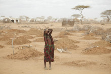 Mladé dievča z utečeneckého tábora Dadaab stojí medzi novými hrobmi 70 detí, z ktorých mnohé zomreli na podvýživu. FOTO: Andy Hall/Oxfam