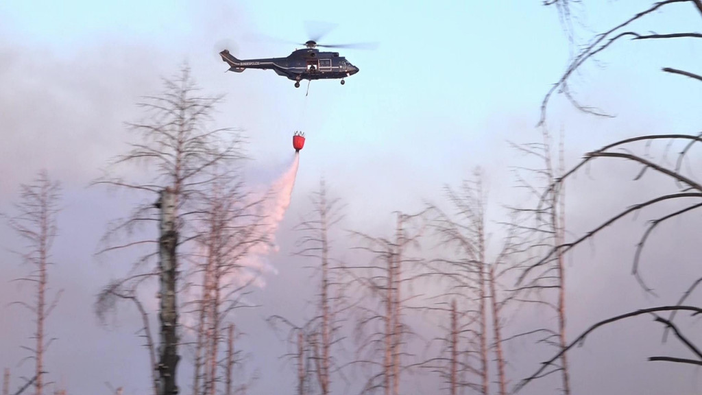 Vrtuľník vylieva vodu z vaku počas lesného požiaru v oblsti s nevybuchnutou muníciou neďaleko historického mesta Jüterbog. FOTO: TASR/DPA