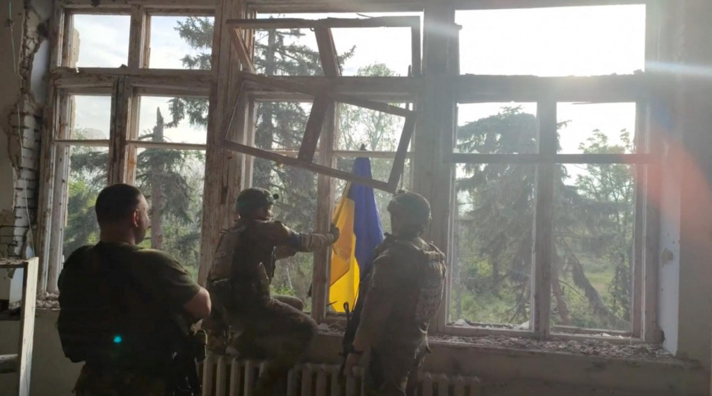 Ukrajinskí vojaci vešajú vlajku po oslobodení obce Blahodatne v Doneckej oblasti. FOTO: Reuters