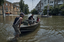 Ľudia so psíkmi sú evakuovaní na loďke zo zaplavených oblastí v ukrajinskom meste Cherson. FOTO: Tasr

