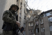 Ukrajinský vojak stojí pred budovou, ktorú zničil ruský raketový útok v meste Cherson na juhu Ukrajiny. FOTO: TASR/AP