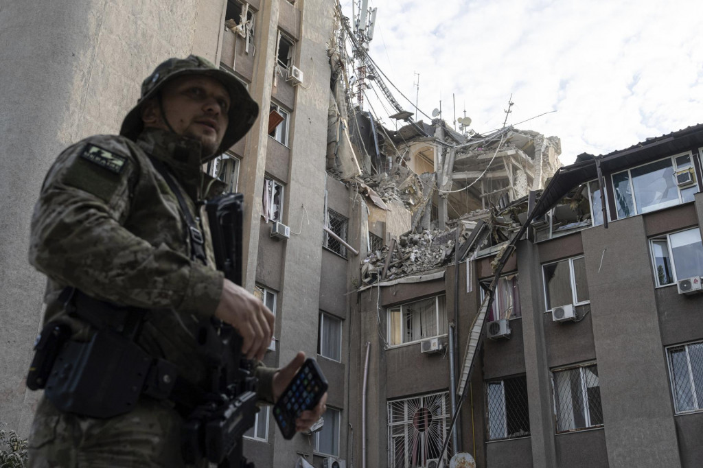 Ukrajinský vojak stojí pred budovou, ktorú zničil ruský raketový útok. FOTO: TASR/AP