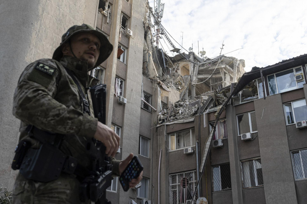 Ukrajinský vojak stojí pred budovou, ktorú zničil ruský raketový útok v meste Cherson na juhu Ukrajiny. FOTO: TASR/AP