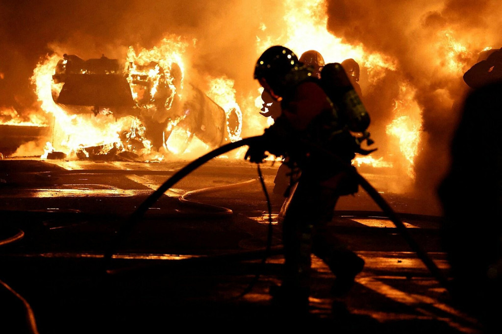 Francúzski hasiči hasia vozidlá počas stretov medzi demonštrantmi a políciou. FOTO: Reuters