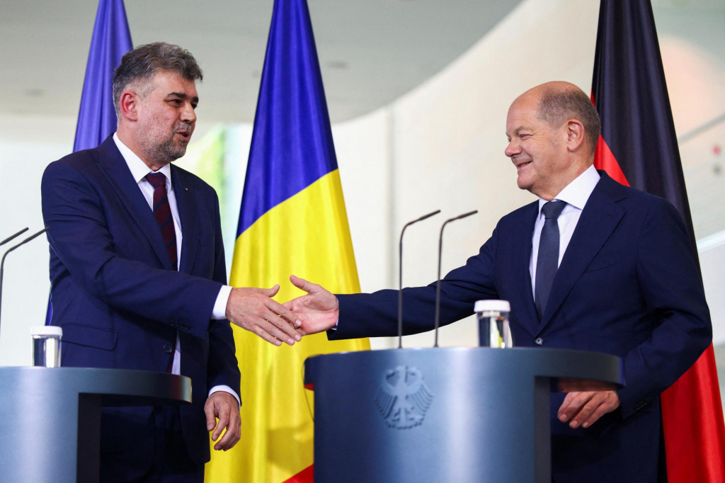 Nemecký kancelár Olaf Scholz si podáva ruku s rumunským premiérom Marcelom Ciolacuom. FOTO: Reuters